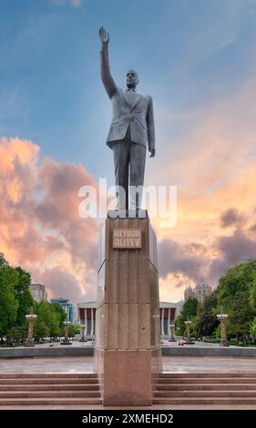 Statue en laiton de Heydar Aliyev à Bakou, Azerbaïdjan, dédiée à l'ancien président azerbaïdjanais, sur la place Heydar Aliyev face au soleil couchant, devant un palais qui porte le nom du président Banque D'Images