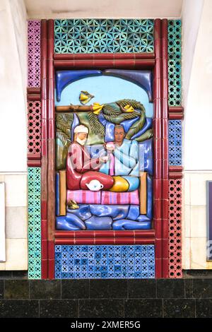Vue d'une scène de frise de mosaïque de tuiles de deux hommes prenant le thé sur un haut jon à la station Chilanzar du métro souterrain, métro à Tachkent, Ouzbékistan Banque D'Images