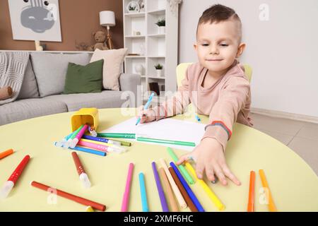 Drôle petit garçon dessin avec des stylos à pointe feutre à table dans la chambre Banque D'Images