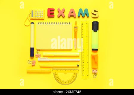 Composition avec différents articles de papeterie et EXAMEN DE mot fait de lettres colorées sur fond jaune Banque D'Images