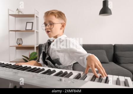 Mignon petit garçon jouant synthétiseur moderne à la maison Banque D'Images