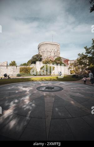 Château de Windor, Royaume-Uni - 16 octobre 2023 : Une boussole en pierre avec un design en étoile au centre se trouve devant une tour du château. Banque D'Images