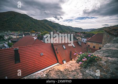 Autriche - 26 octobre 2023 : vue sur les toits de tuiles rouges d'une petite ville européenne, prise depuis une falaise rocheuse surplombant la vallée. Banque D'Images