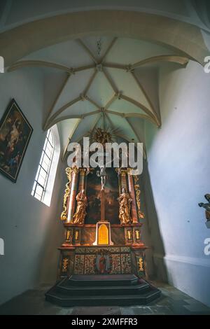 Autriche - 26 octobre 2023 : Un autel orné d'or se dresse à l'intérieur d'une église en Autriche, ses détails richement décorés sur fond d'une voûte Banque D'Images