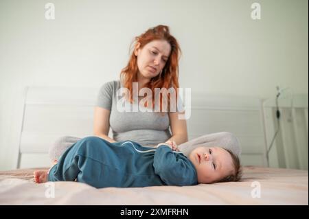 Femme avec dépression post-partum assise sur le lit à côté du nouveau-né. Banque D'Images