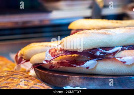 Gros plan sur les célèbres sandwichs ibériques de Salamanca, jambon ibérique. La viande est empilée sur un pain grillé, roulé et est un repas populaire à Salamanque Espagne. Banque D'Images