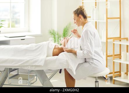 Femme satisfaite utilise les services d'esthéticienne professionnelle dans un salon de beauté ou un spa. Banque D'Images