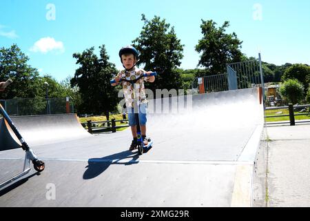 Jeune garçon s'amusant sur son scooter dans un skate Park -John Gollop Banque D'Images