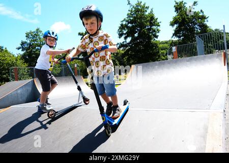 Jeune garçon s'amusant sur son scooter dans un skate Park -John Gollop Banque D'Images