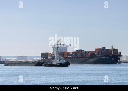 Le Havre, France - vue sur le porte-conteneurs MERKUR FJORD au départ du port du Havre avec un remorqueur remorquant une barge à son côté. Banque D'Images