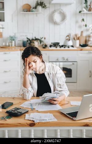Femme caucasienne stressée essayant de traiter avec des documents financiers, ayant du mal à trouver de l'argent pour payer des factures de services publics ou des prêts. Le concept de dette Banque D'Images