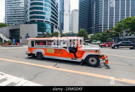 Manille, Philippines - 26 août 2019 : un jeepney vibrant fait son chemin à travers une intersection animée à Makati. Banque D'Images