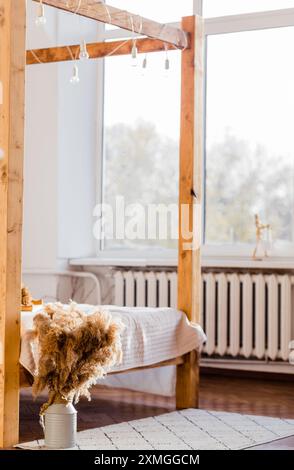 Chambre confortable de style bohème avec cadre de lit en bois et lumière naturelle douce. Photo verticale. Banque D'Images