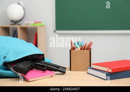 Papeterie scolaire, pistolet et sac à dos sur le bureau en classe Banque D'Images