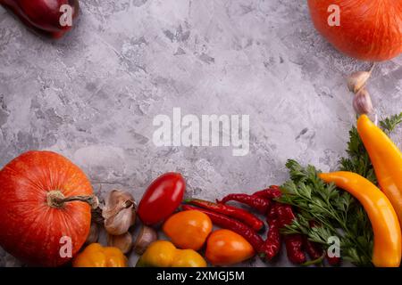 Une variété de légumes frais et de citrouilles sont affichés sur un fond gris rustique Banque D'Images