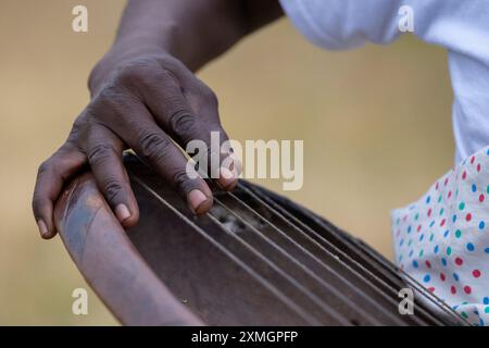 Rwanda, Virunga Lodge. Volcanoes Safaris Partnership Trust (VSPT) manifestations culturelles traditionnelles. Homme jouant un instrument à cordes en bois typique. Banque D'Images