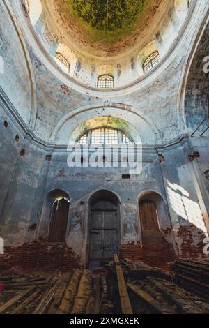 Vue intérieure d'une église abandonnée, mettant l'accent sur la détérioration du dôme avec de la peinture écaillée et de la brique exposée, capturant le vieillissement et le weat de la structure Banque D'Images