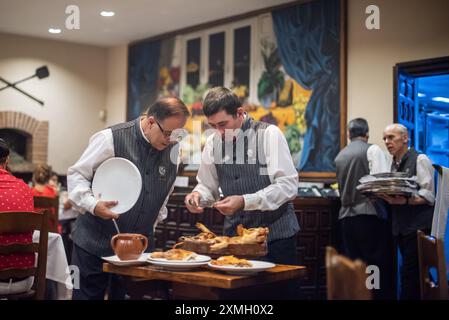 Serveurs servant des cochons de lait rôtis au célèbre restaurant Jose Maria à Ségovie, Castilla y Leon, Espagne. Une expérience culinaire vibrante et traditionnelle Banque D'Images