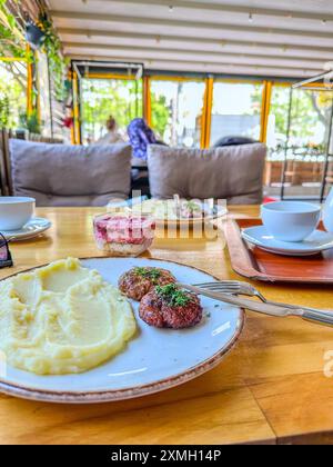 Déjeuner au restaurant. Une portion de galettes de bœuf à la russe avec purée de pommes de terre et herbes. En arrière-plan - salade avec betterave et Banque D'Images