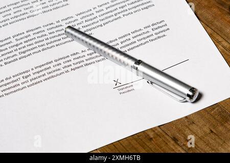 Formulaire de contrat papier avec une signature sur le point d'être signée dans un champ de signature. Banque D'Images