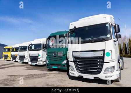 plusieurs camions stationnés bien en rangée dans le parking par une journée ensoleillée. vue des cabines de tracteurs-remorques de différentes couleurs. Véhicules utilitaires, ad Banque D'Images