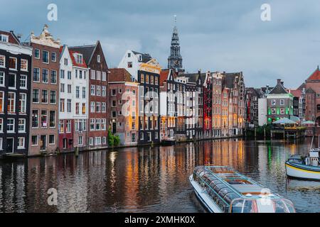 Vue panoramique sur le canal d'Amsterdam avec maisons traditionnelles et bateau au crépuscule Banque D'Images