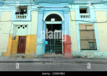 548 Maison éclectique de façade jaune citron, moulure bleu pâle, fenêtres barrées, porte de grille, porte en bois massif, Bartolome Maso Street. Santiago-Cuba. Banque D'Images