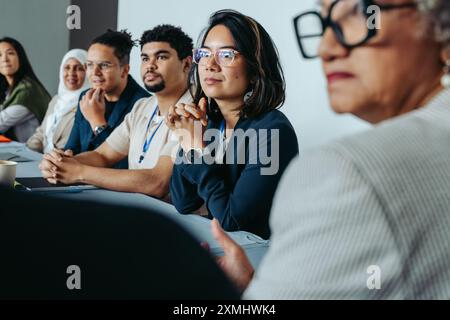 Un groupe diversifié de professionnels dans une réunion de conseil d'administration, concentré et attentif, suggérant collaboration et travail d'équipe. Banque D'Images