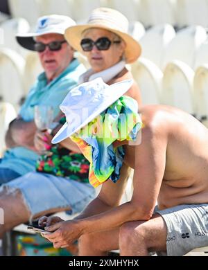 Hove UK 28 juillet 2024 - les fans apprécient le soleil chaud et restent protégés des rayons pendant qu'ils regardent le match de cricket entre les requins du Sussex et le Warwickshire au 1er Central County Ground à Hove : crédit Simon Dack /TPI/ Alamy Live News Banque D'Images