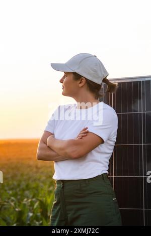 Femme portant un chapeau blanc se tient à côté du panneau solaire au coucher du soleil. Banque D'Images