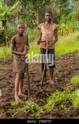 FORT PORTAL, OUGANDA - 12 MARS 2020 : enfants locaux travaillant dans un champ près du lac Nyamirima dans la région des lacs de cratère près de Fort Portal, Ouganda Banque D'Images