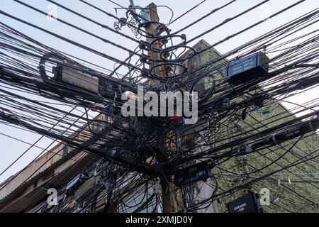 Enchevêtrement sauvage de lignes électriques et de télécommunications sur un poteau de service à Bangkok, Thaïlande. Banque D'Images