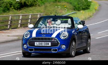 Milton Keynes, Royaume-Uni - 28 juillet 2024 : femme conduisant une Mini voiture bleue à toit ouvert 2018 conduisant sur une route britannique Banque D'Images