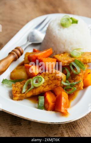 Tempeh aigre-doux avec courge uchi kuri rouge et riz dans une assiette. Banque D'Images