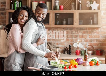 Reconnaissant femme serrant son mari par derrière en cuisine Banque D'Images