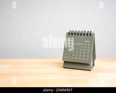 Un calendrier de bureau août 2024 pour plan et rappel isolé sur table en bois et fond gris avec espace copie, style éco. Petit calendrier vert avec Banque D'Images