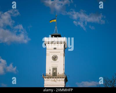Lviv, Ukraine - 26 mars 2024 : la tour de la mairie de Lviv avec une horloge et le drapeau de l'Ukraine Banque D'Images