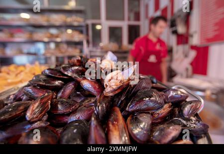 Saveurs de rue moules farcies. Moule tenant la main. Tas de mollusques noirs. Banque D'Images