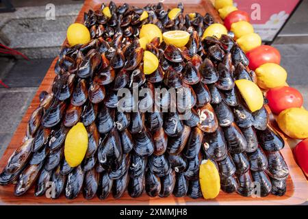 Saveurs de rue moules farcies. Moule tenant la main. Tas de mollusques noirs. Banque D'Images