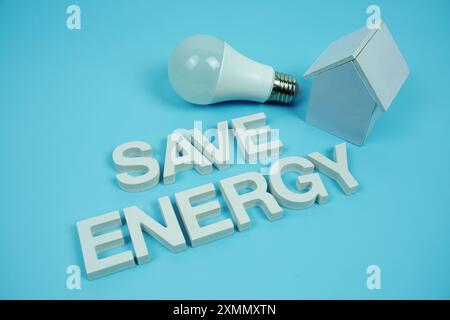 Économisez l'énergie lettres de l'alphabet avec modèle de maison et ampoules LED sur fond bleu, économie et concept respectueux de l'environnement Banque D'Images