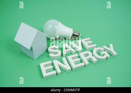 Économisez l'énergie lettres de l'alphabet avec modèle de maison et ampoules LED sur fond vert, économie et concept respectueux de l'environnement Banque D'Images