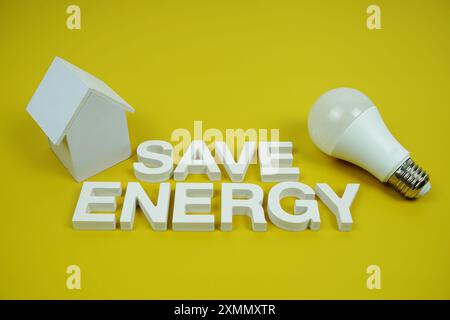 Économisez l'énergie lettres de l'alphabet avec le modèle de maison et les ampoules LED sur fond jaune, économie et concept respectueux de l'environnement Banque D'Images