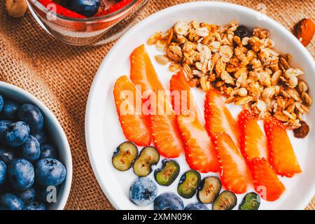 Granola avec fraises et bleuets avec lait ou yaourt dans un bol blanc. Photo de haute qualité Banque D'Images
