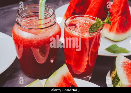 Jus de pastèque fraîchement pressé et smoothie à la pastèque avec pastèque tranchée sur fond gris. Photo de haute qualité Banque D'Images