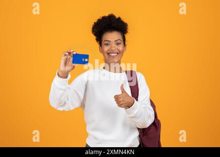 Femme souriante tenant la carte de crédit et donnant Thumbs Up Banque D'Images