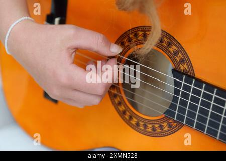 Teenage Girl joue de la guitare acoustique clsoe vers le haut du trou sonore Banque D'Images