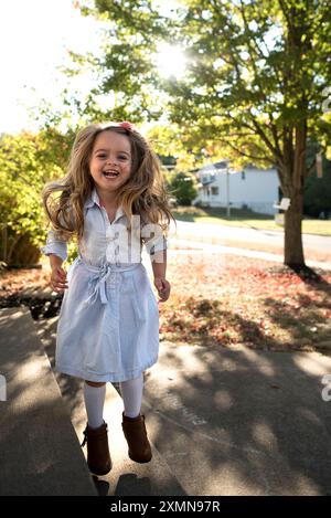 Belle petite fille heureuse sautant souriant le jour ensoleillé Banque D'Images