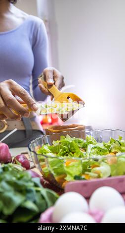 Femme prépare une salade saine dans un bol en verre. Banque D'Images