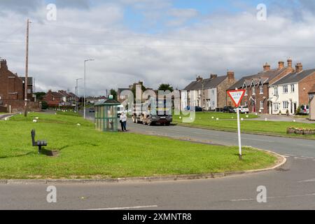 Trimdon, comté de Durham, Royaume-Uni. Les gens attendent à l'arrêt de bus sur Front Street dans le village. Banque D'Images