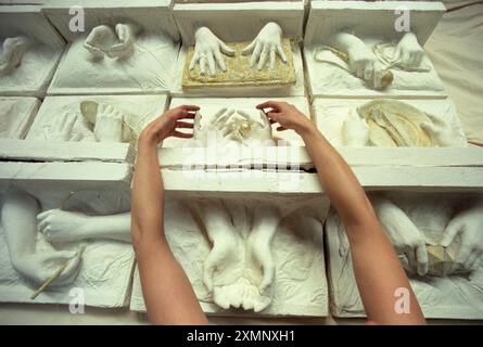 Une femme artiste arrangeant des moulages en plâtre de mains de femmes symbolisant le travail de femmes dans le monde vaut son poids en or quelques-uns des 99 moulages en plâtre de mains de femmes exposées dans le travail de femmes dans le monde vaut son poids en or à la Fabrica galerie Brighton . Les moulages chacun par une femme différente ont pris plus de 15 heures chacun pour faire 8 mars 2000 photo de Roger Bamber Banque D'Images